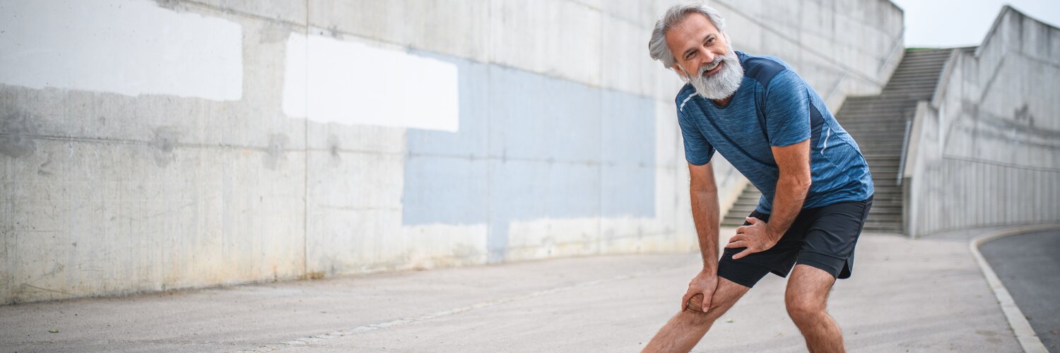 Älterer Mann dehnt sich beim Joggen