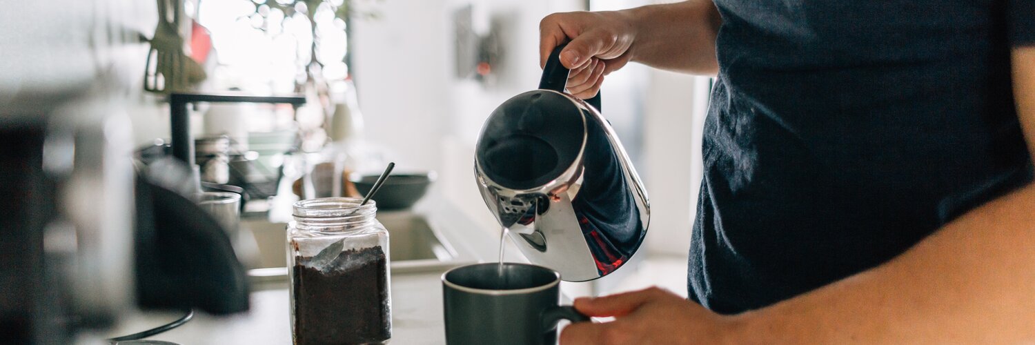 Mann gießt Tee in einer Tasse auf