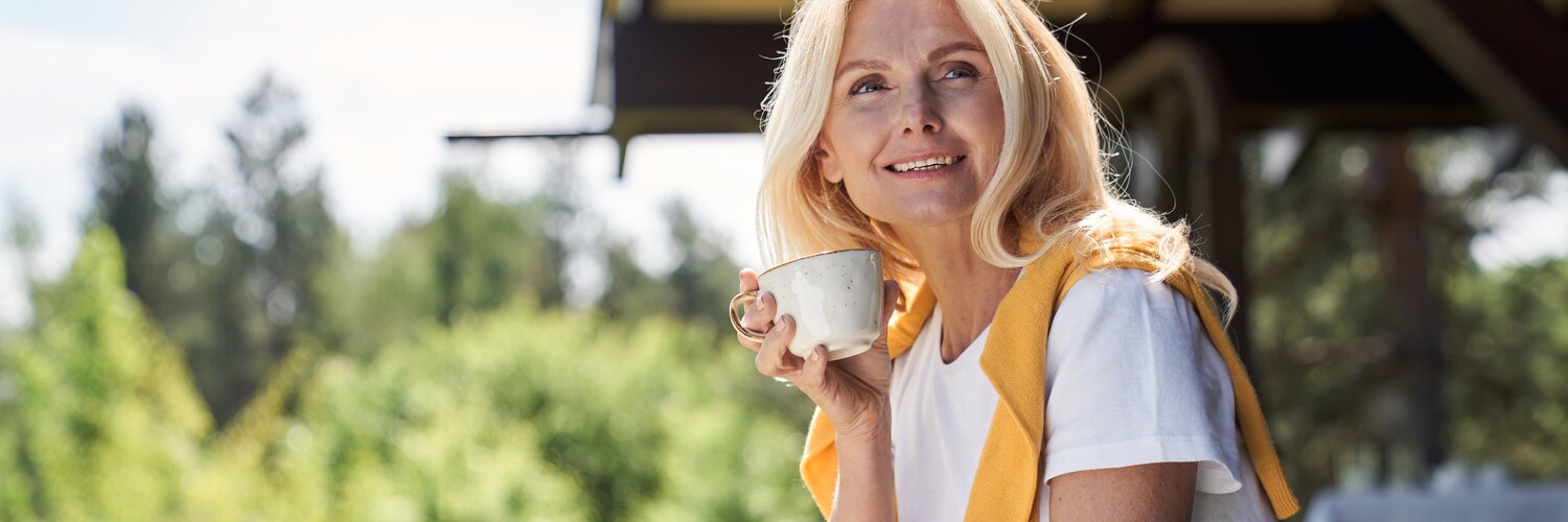 Frau sitzt auf der Terrasse und trinkt eine Tasse Tee