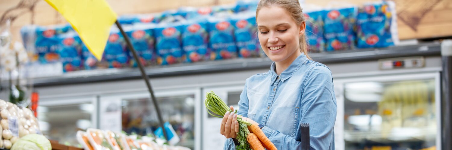 Frau kauft Lebensmittel wie Karotten im Supermarkt ein