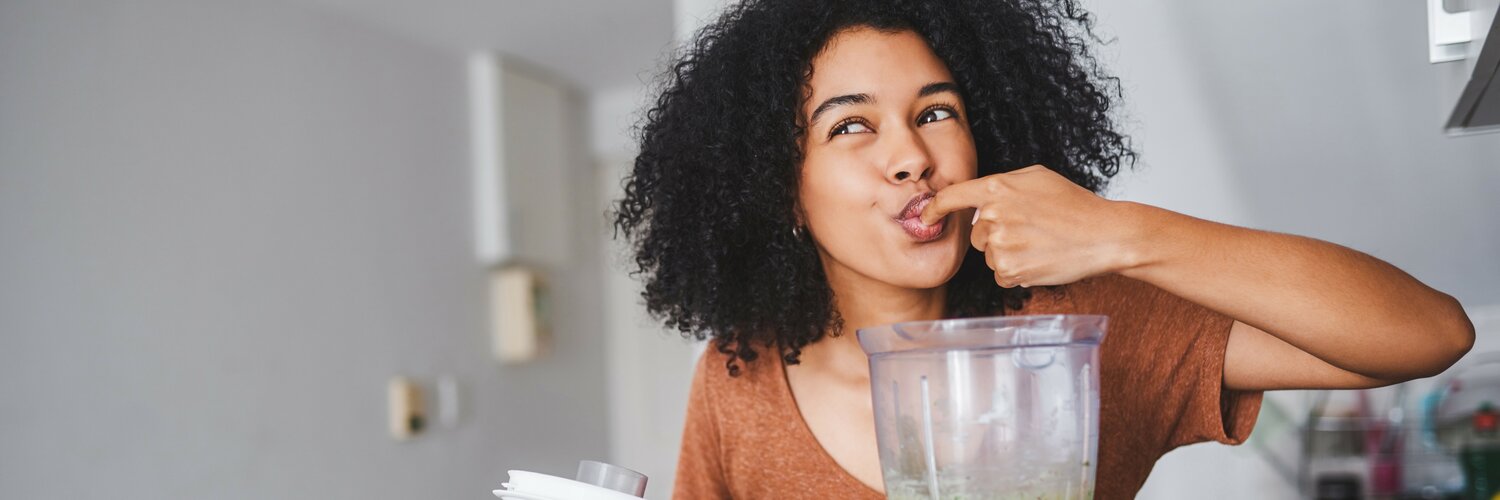 Frau macht sich einen grünen Smoothie im Mixer
