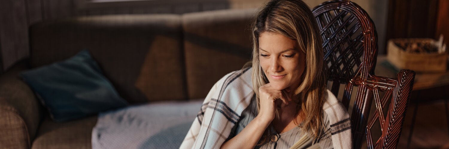 Frau liest im Schaukelstuhl ein Buch