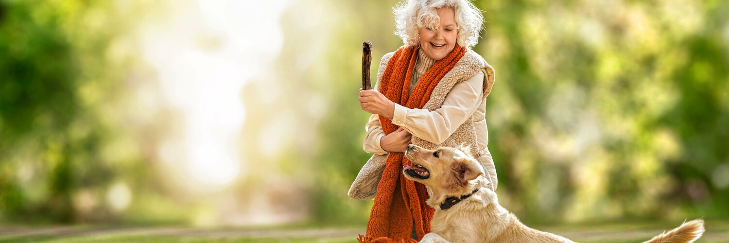 Frau spielt draußen mit ihrem Hund
